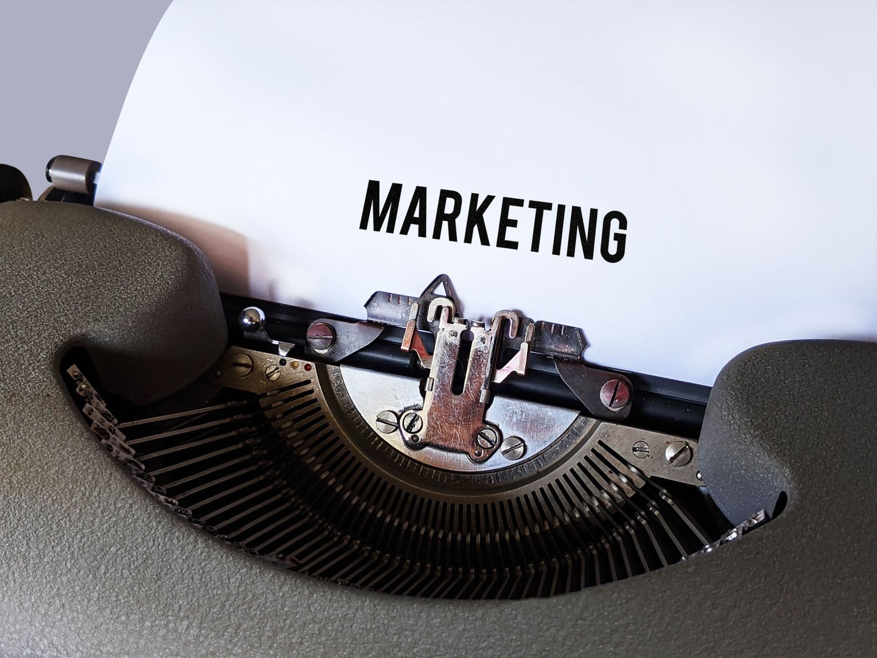 Nahaufnahme einer Vintage-Schreibmaschine mit dem Wort 'Marketing' auf dem Papier, was ein retro Geschäftsthema vermittelt.